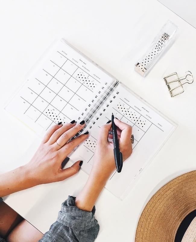 Ręce rozpisujące plan w kalendarzu, czyli produktywność w pracy