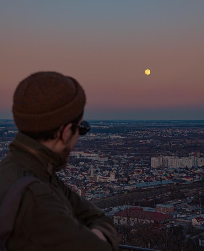 Mężczyzna i pełnia księżyca nad miastem